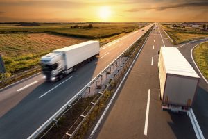 Two trucks on highway in motion blur at sunset