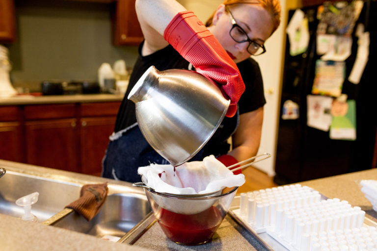 Woman pours liquid into glass jar.