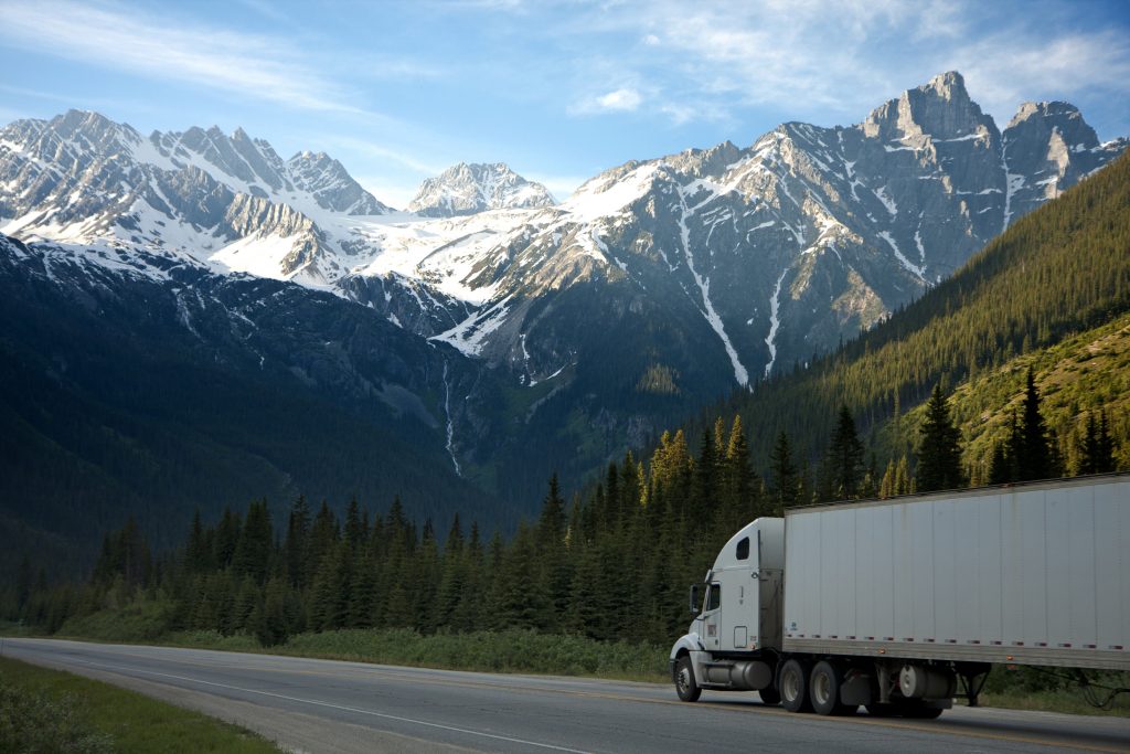 A truck drives down the road against a mountainous background