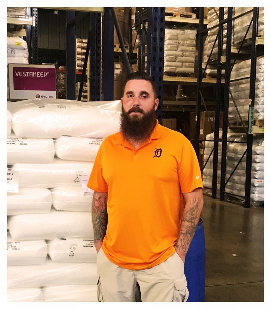 Man with beard stands against a background with racks