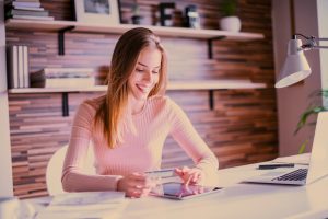 Woman holds credit card, purchasing something online.